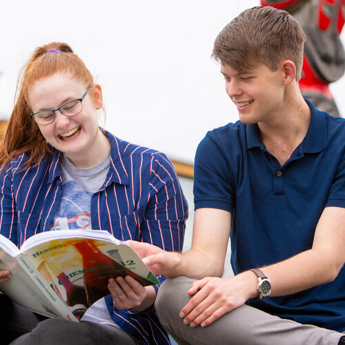 Two teens reading a textbook together